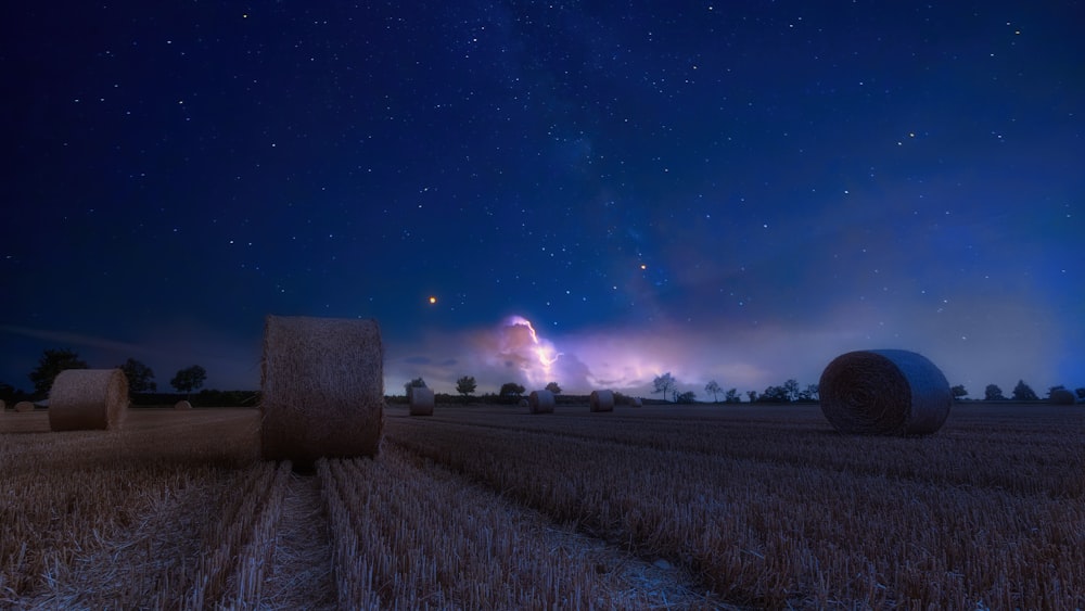 a field with hay bales under a night sky