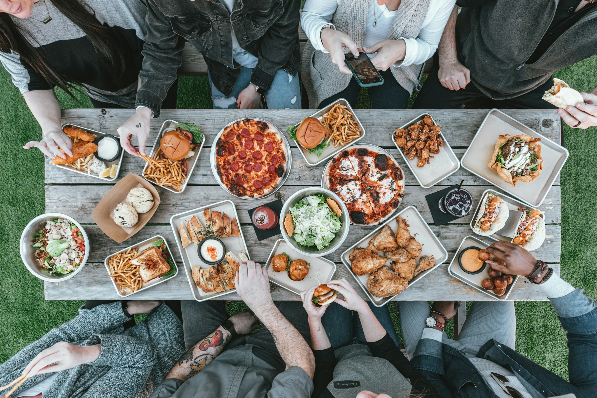 A long table from above, covered in shared plates, people standing around it.