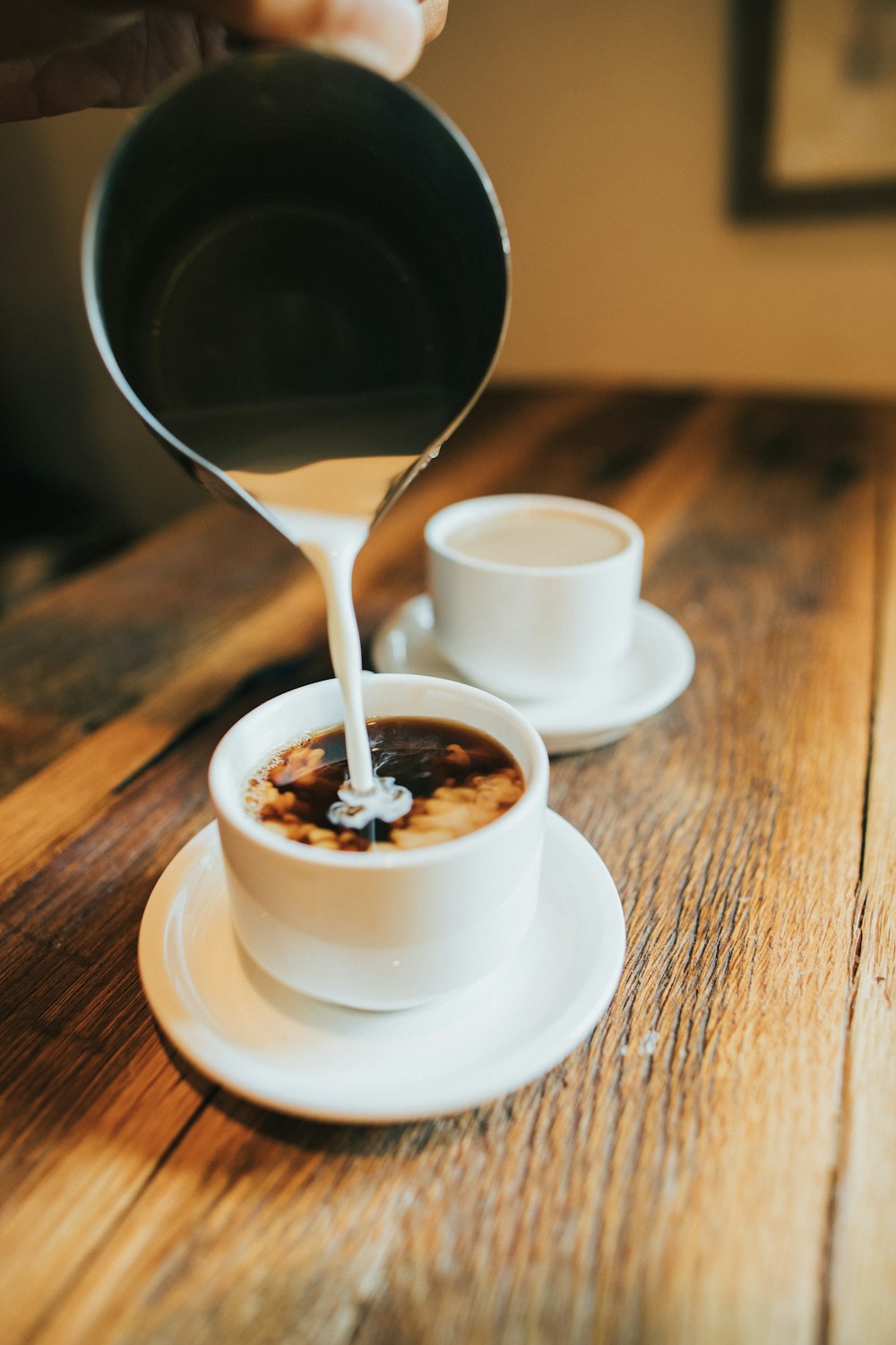 person pouring milk on white cup