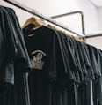 hanged black t-shirts beside wall