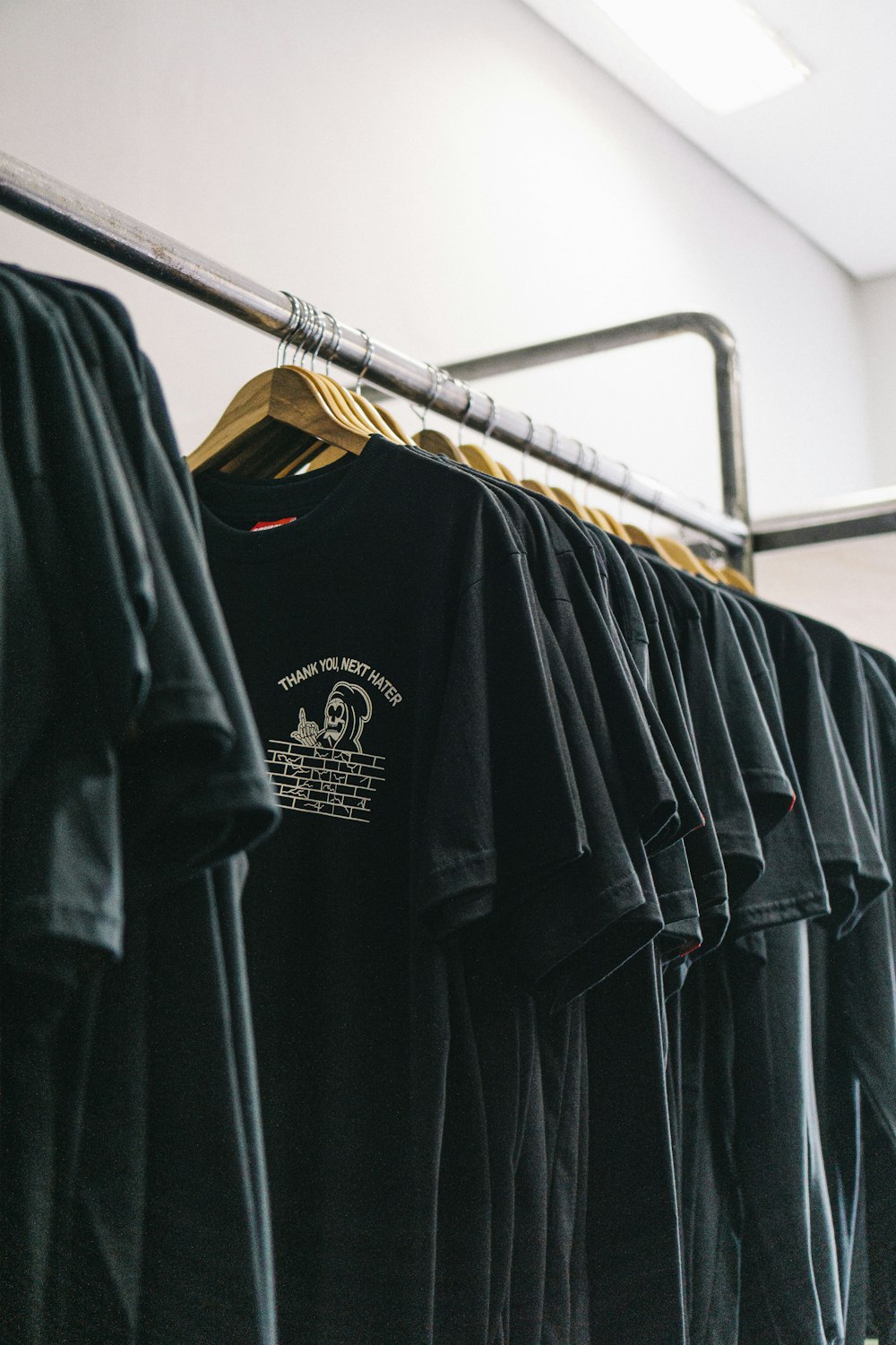 hanged black t-shirts beside wall