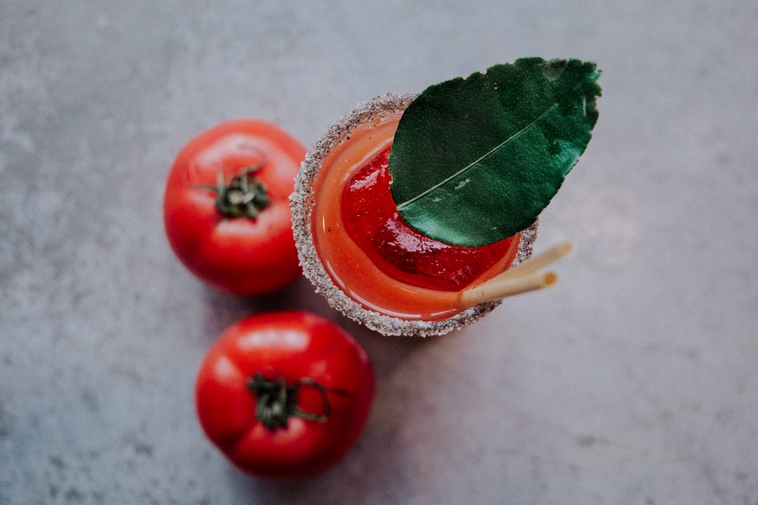 two red tomatoes beside tomato juice cup