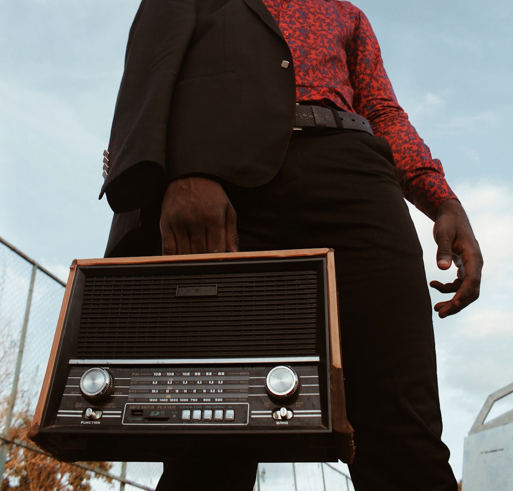 selective focus photography of standing man carrying black and gray radio