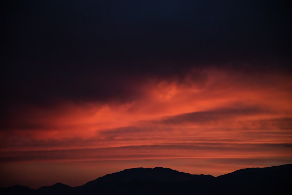 silhouette of mountain under cloudy sky during golden hour