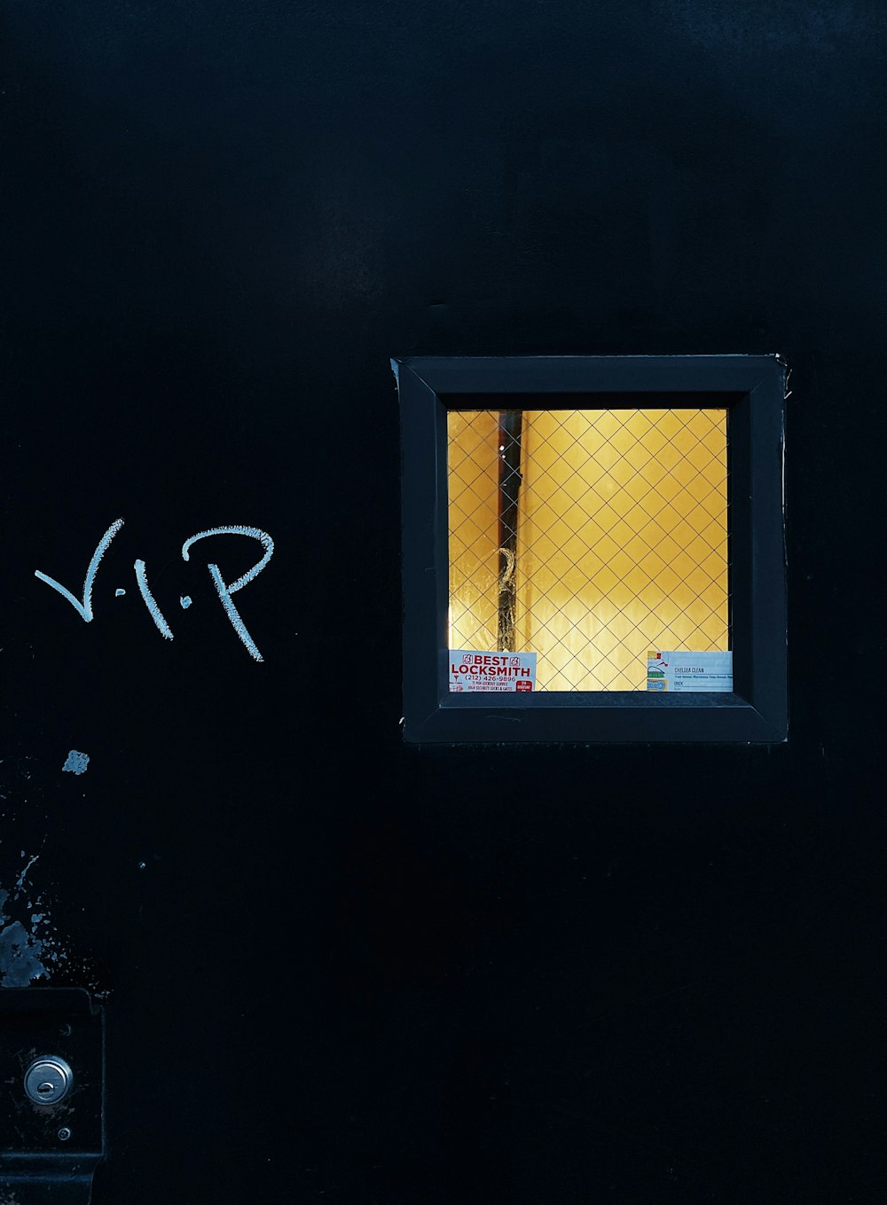 a black wall with a window and graffiti on it