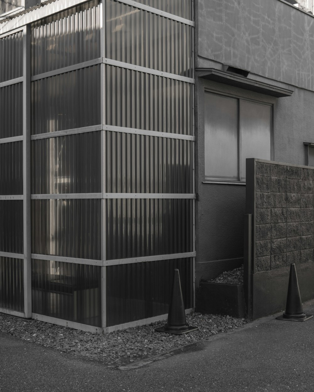 grayscale photography of road cones beside wall