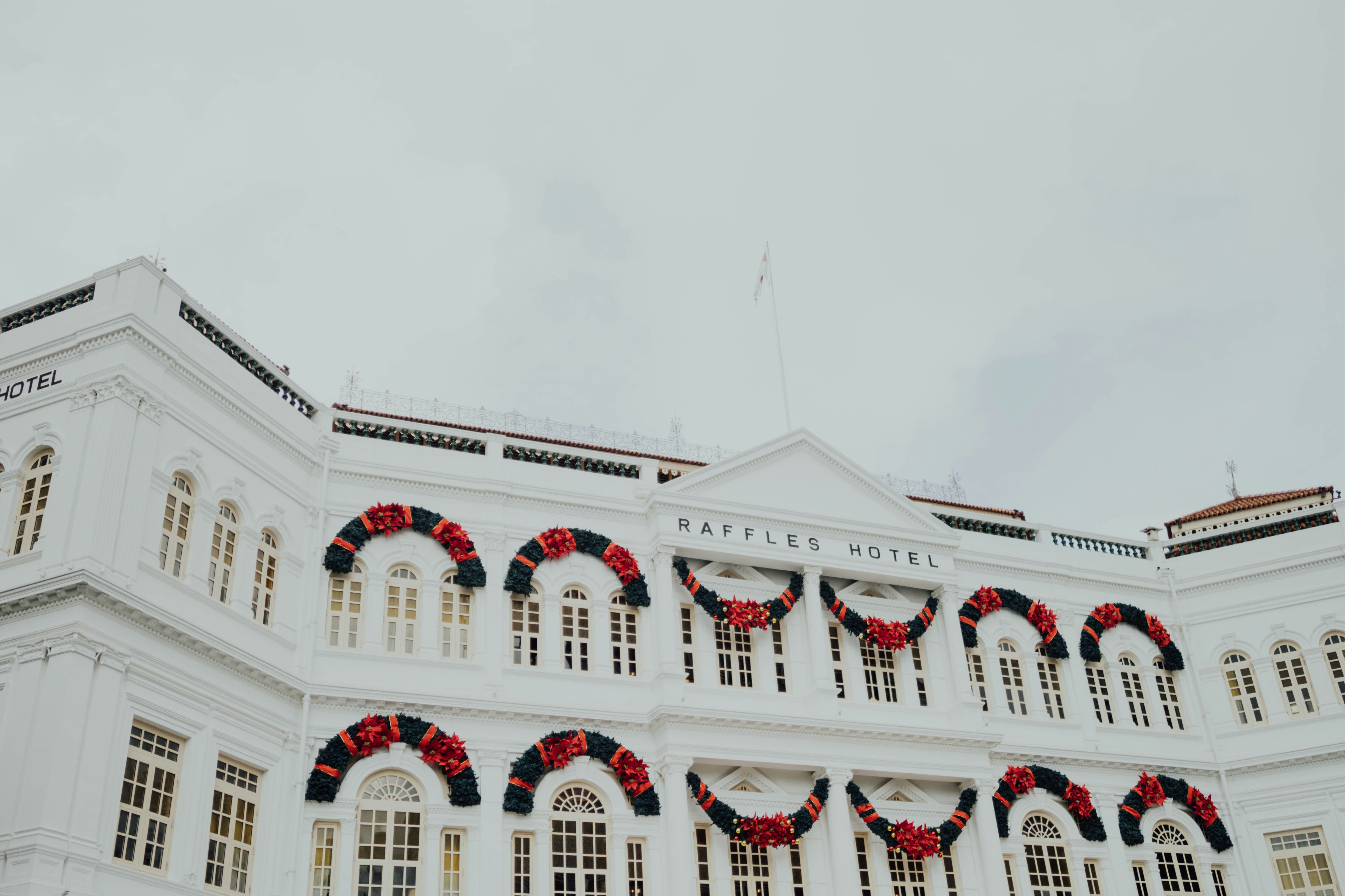 The sunlit facade of a grand colonial-style hotel building with palm trees.