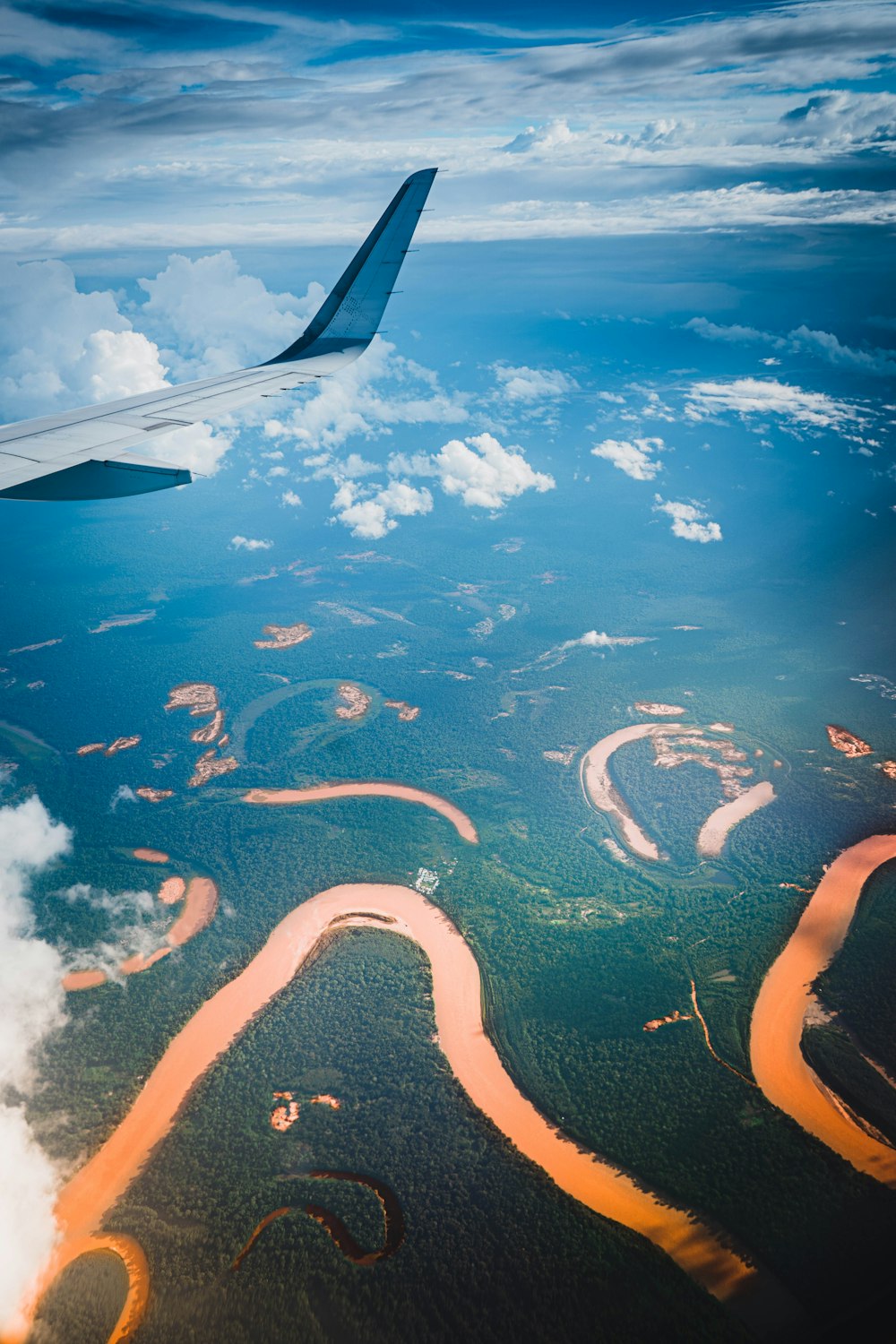 an airplane wing flying over a river and land