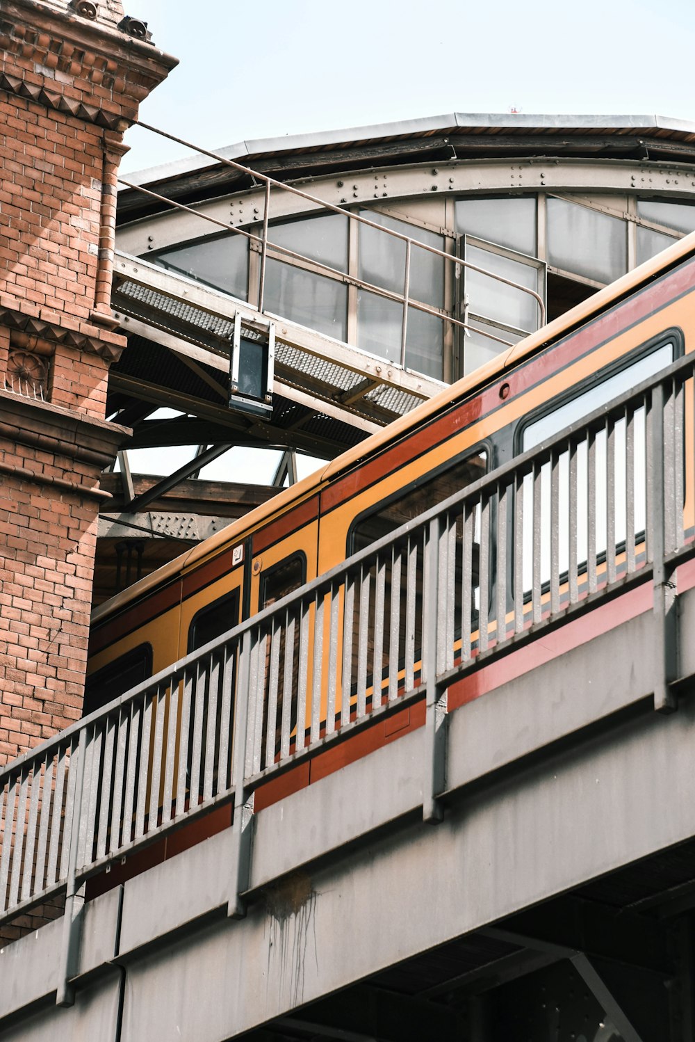 a yellow train traveling over a bridge next to a tall brick building