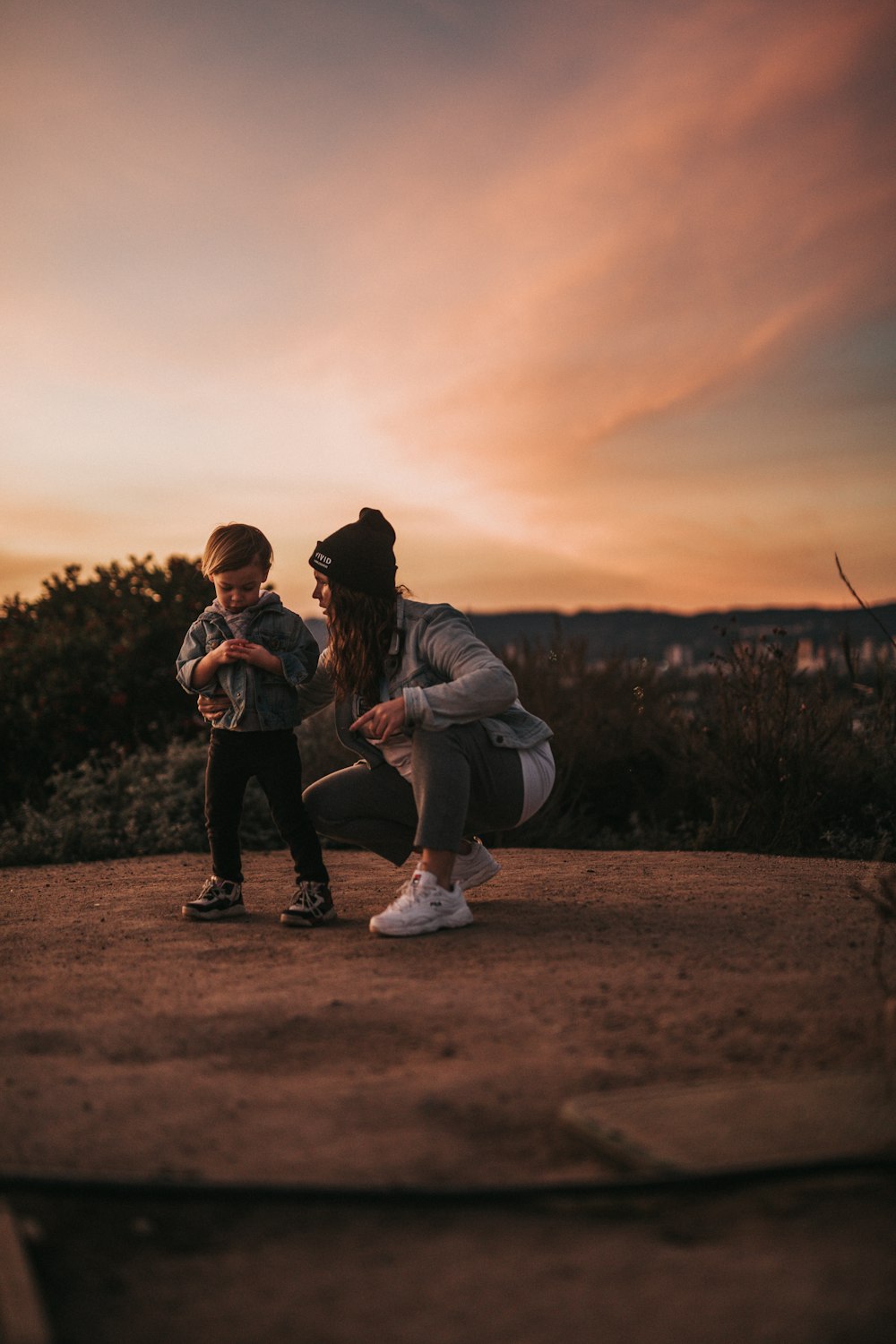 a woman kneeling down next to a little boy