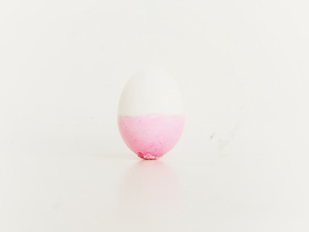 a pink and white egg on a white surface
