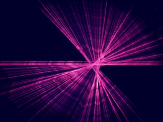 Bright pink laser beams intersect against a dark background, creating an abstract geometric pattern. The lines converge at a central point and spread outward in multiple directions.