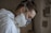 A person wearing protective gear, including a white coverall and a respirator mask, appears to be focused and working in a potentially hazardous environment. The setting suggests a professional or industrial context.
