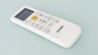 A white remote control with a digital display and several buttons, including a prominent yellow 'START/STOP' button, designed for operating an electronic device. The brand name 'marQ' is visible on the lower part of the remote. The buttons on the remote include functions for mode, swing, e-saver, timer, display, and others.