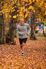 man running on leaf covered field during day
