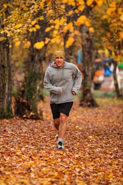 man running on leaf covered field during day