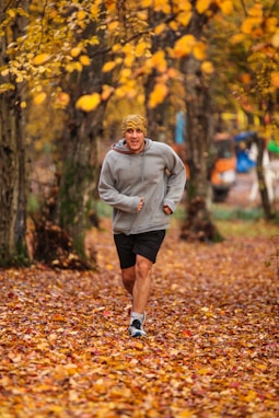 man running on leaf covered field during day