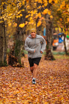 man running on leaf covered field during day