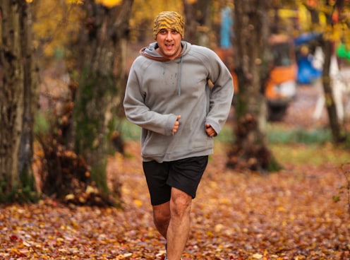 man running on leaf covered field during day