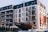 A modern multi-story hotel building with numerous balconies, set against a clear sky. In front of the building is a large boat on display, with the name 'Hotel Gdańsk' visible on the hull. The structure and design suggest a contemporary and clean architectural style.