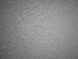 A close-up view of a textured fabric surface with a subtle geometric pattern. The fabric appears to have small, evenly distributed dots creating a sense of depth and dimensionality.