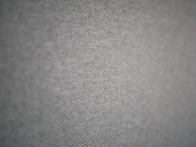 A close-up view of a textured fabric surface with a subtle geometric pattern. The fabric appears to have small, evenly distributed dots creating a sense of depth and dimensionality.