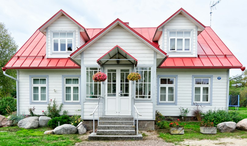 Maison familiale blanche au toit rouge avec jardin fleuri