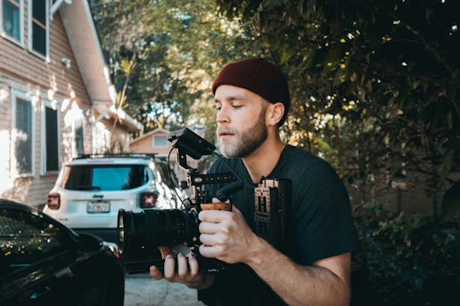 A cameraman filming a home service crew working outdoors on a sunny day.