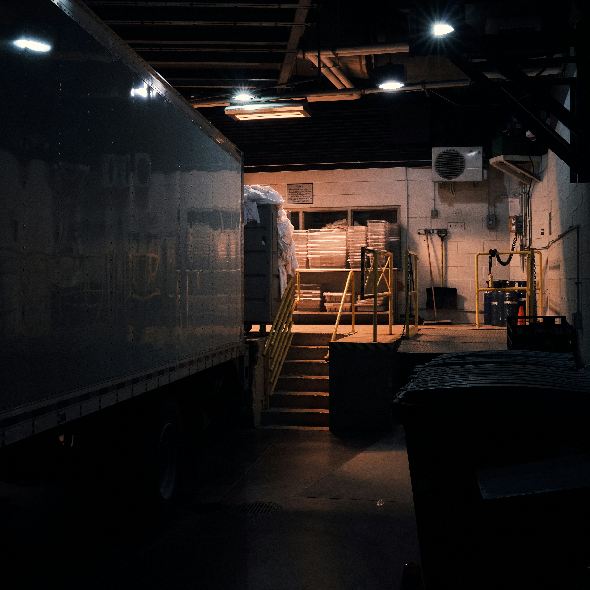 Freight cargo containers at loading dock, well-lit industrial space, organized stacks