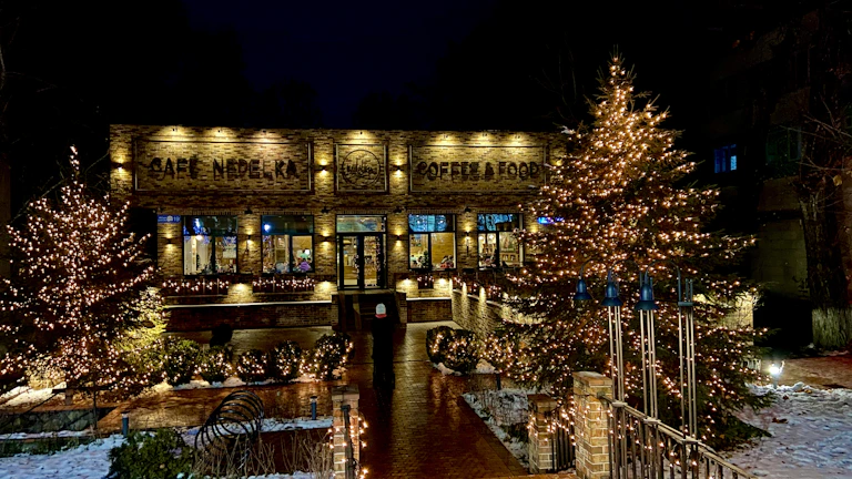 The café storefront at dusk, warmly lit with a welcoming glow and inviting entrance.