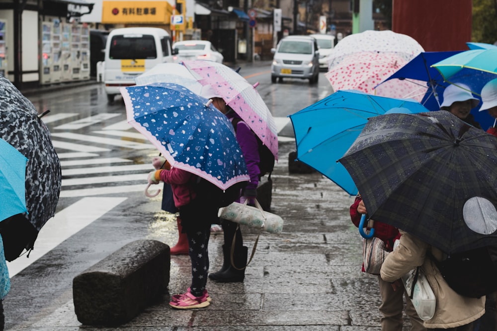 people holding umbrella on sidewalk