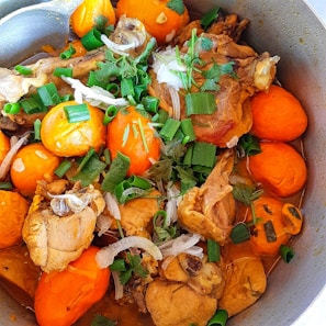 A vibrant bowl of fiery chicken stew bubbling with rich spices and fresh herbs.