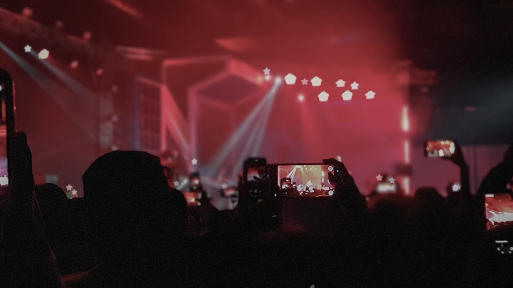 people holding smartphones inside red lighted building