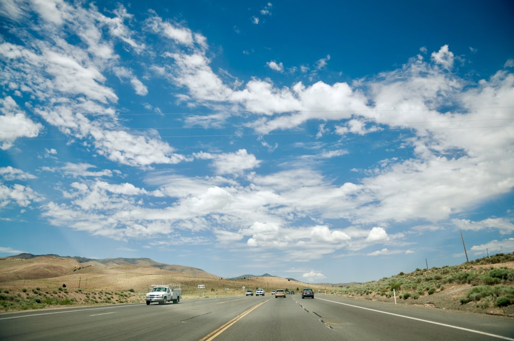 vehicles on road under cloudy sky during daytime