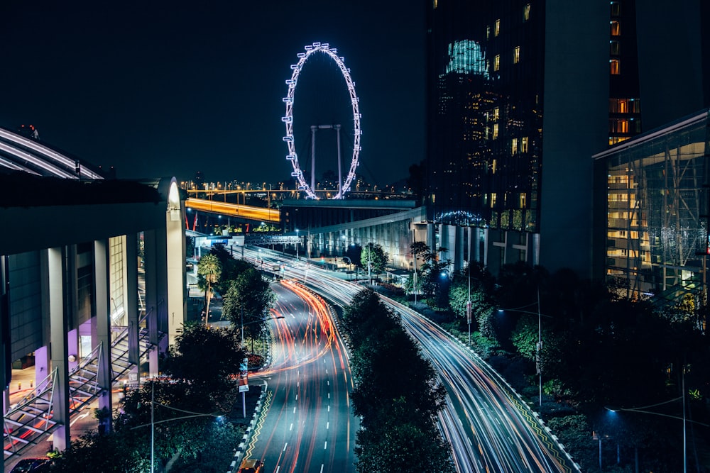 fotografia time-lapse di strade cittadine vicino alla ruota panoramica di notte