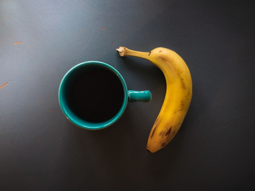 banane jaune à côté de la tasse en céramique verte