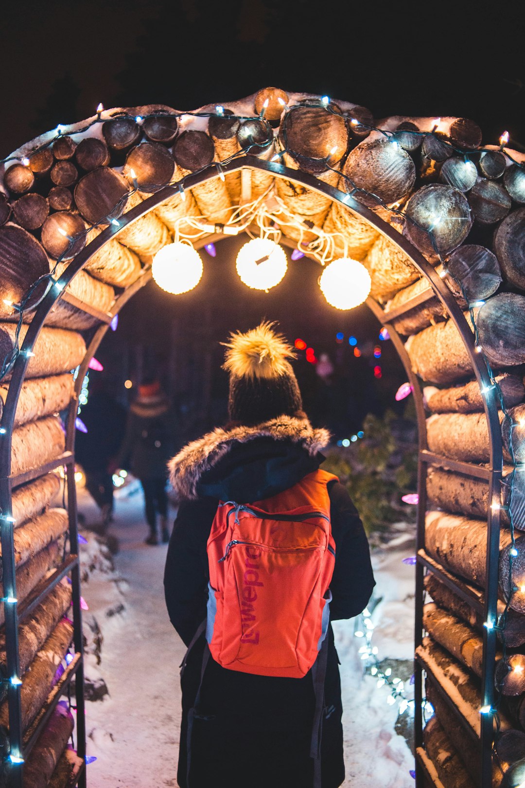 person standing under wooden arch with lights