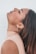 A person in a high-neck, sleeveless top is shown in profile, with their head tilted back and eyes closed. The focus is on their serene expression and the simple, elegant earring worn in one ear.