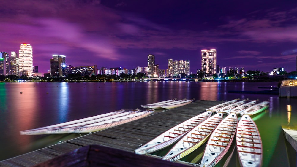 canoe on body of water viewing city with high-rise buildings during night time