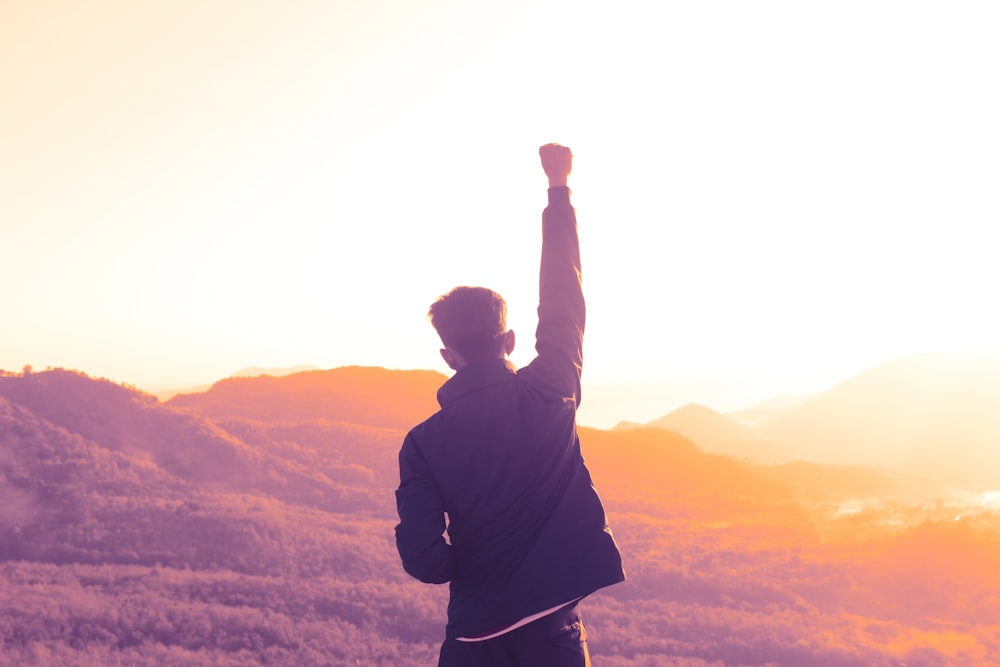 man raising his right arm during day