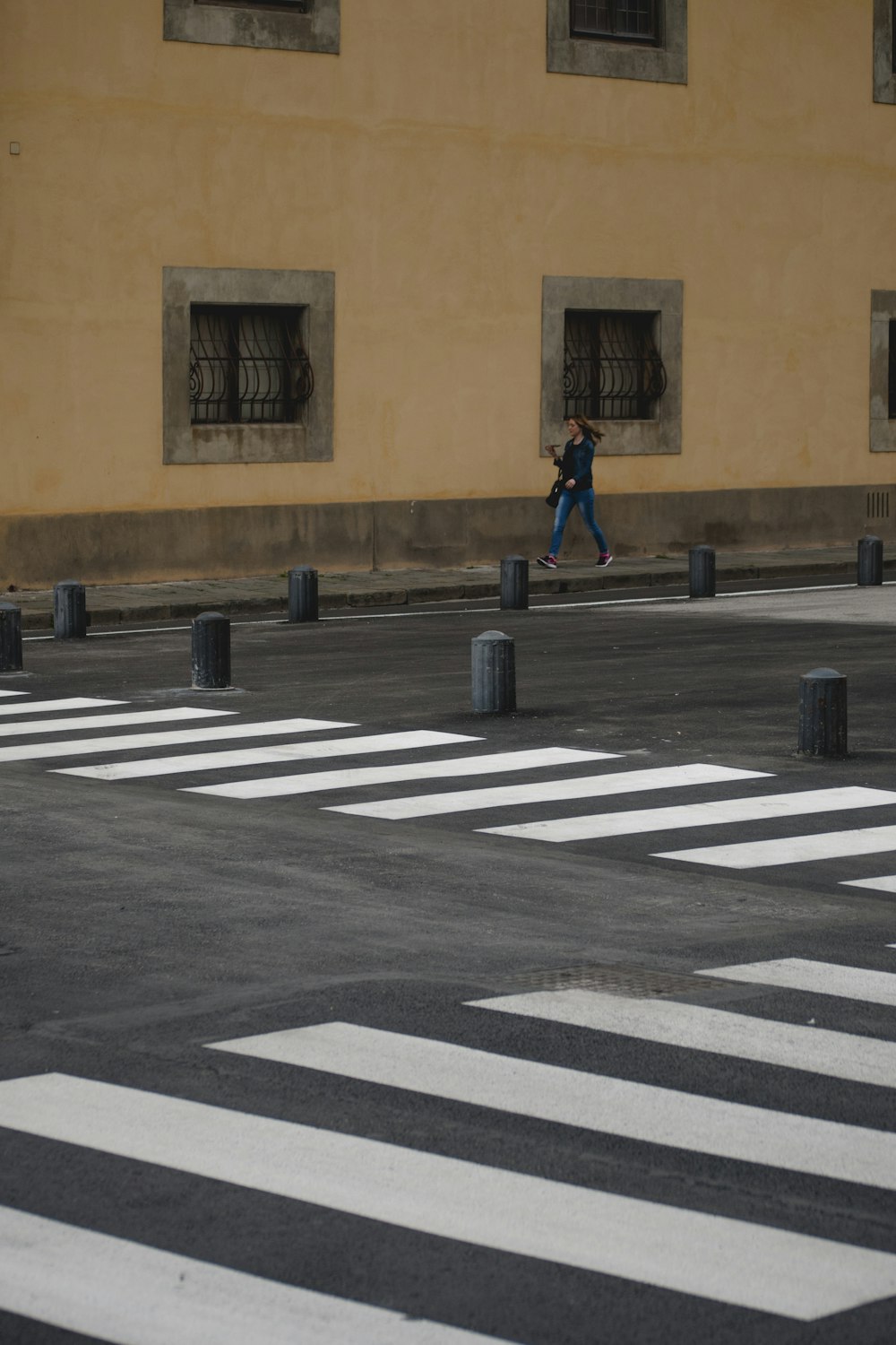 a person walking across a cross walk in front of a building