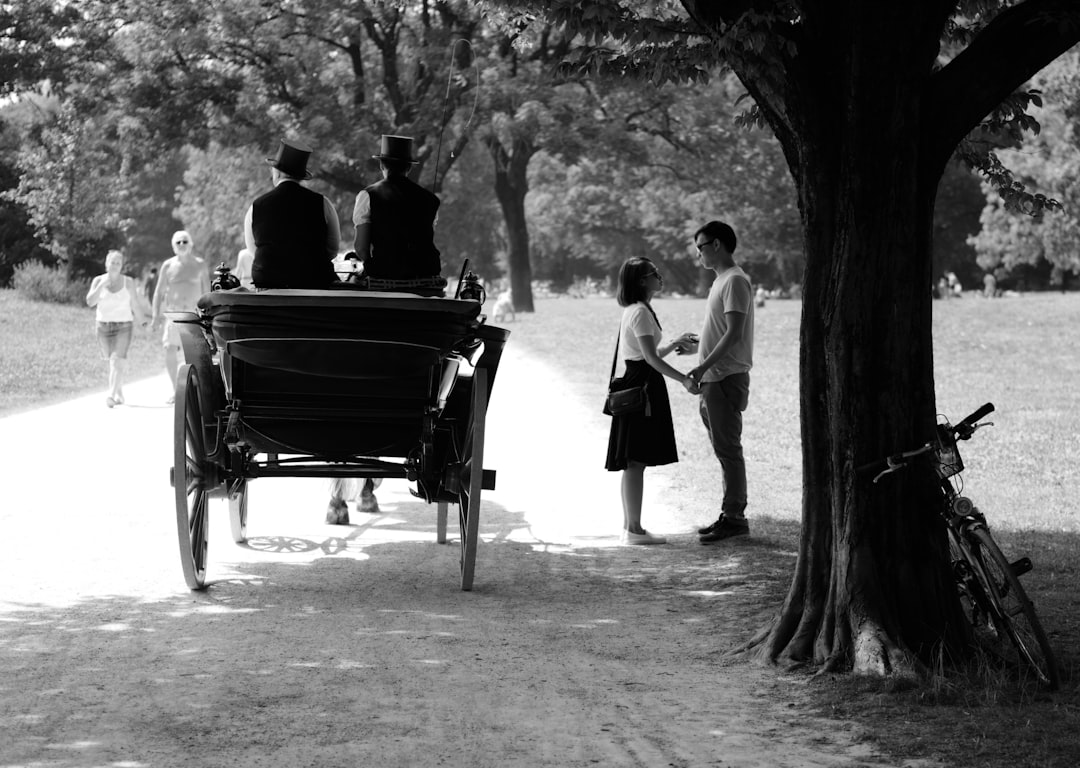 grayscale photography of couple standing beside carriage