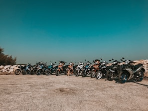 Motorcycles parked in a row at a community event under clear skies.