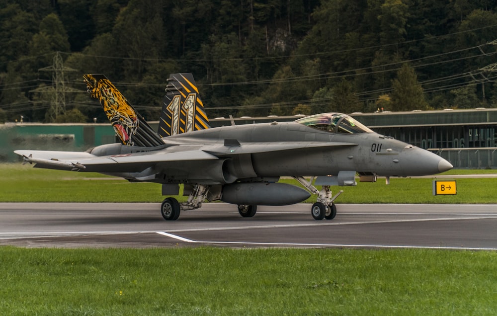 black fighter jet on gray asphalt road during daytime