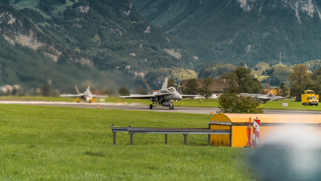 white and yellow plane on green grass field near mountain during daytime