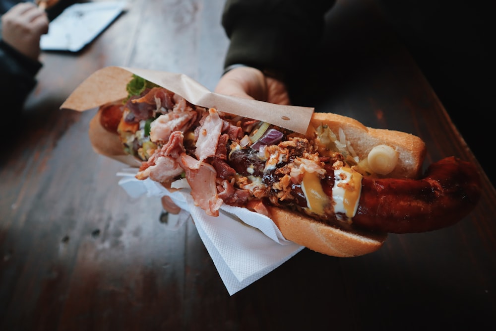 person holding bun with hotdog