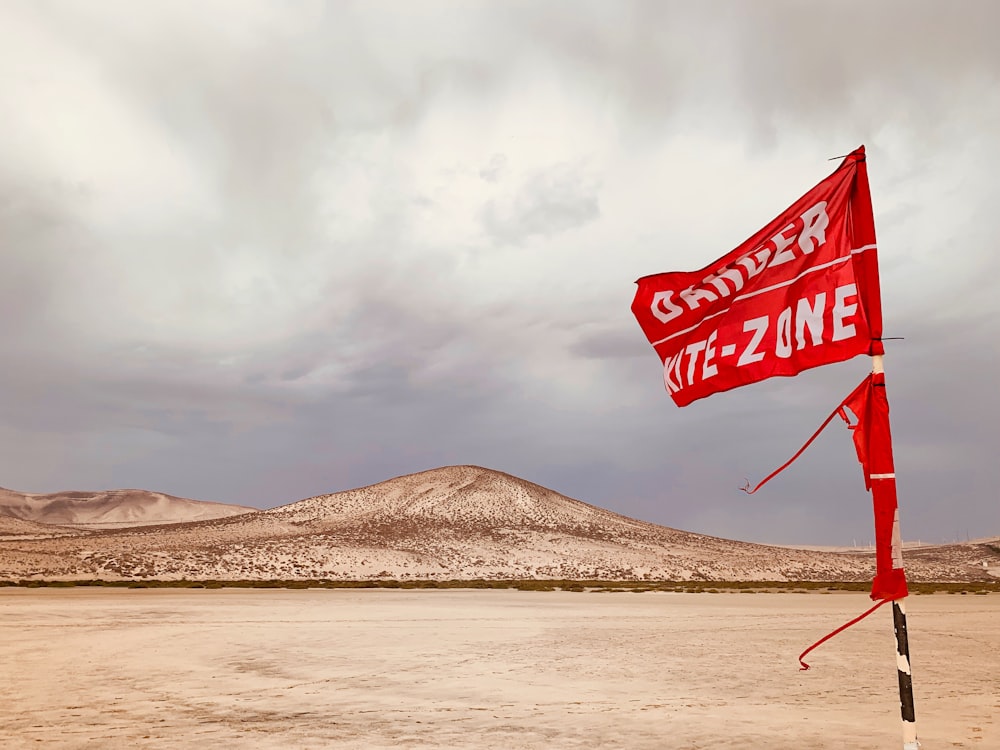 selective focus photography of red and white flag under cloudy sky