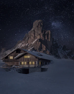 A cozy wooden chalet nestled in snowy mountains at twilight, glowing warmly from inside.