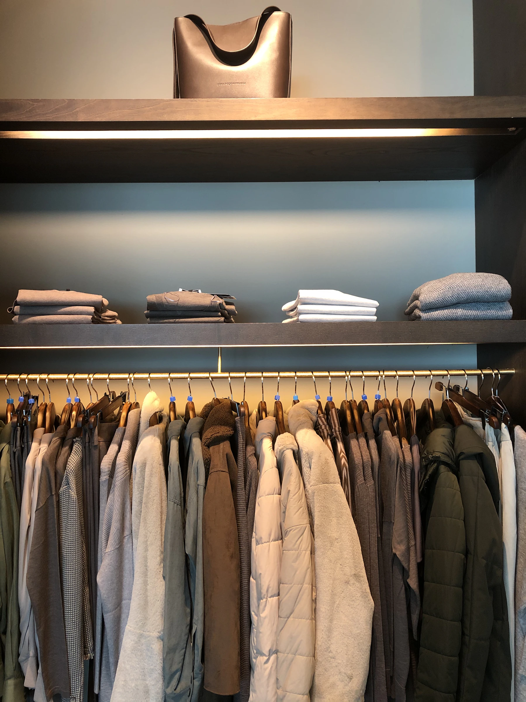 Organized wardrobe with neatly folded clothing above hanging garments