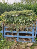 Team members mixing compost materials in large containers outdoors.